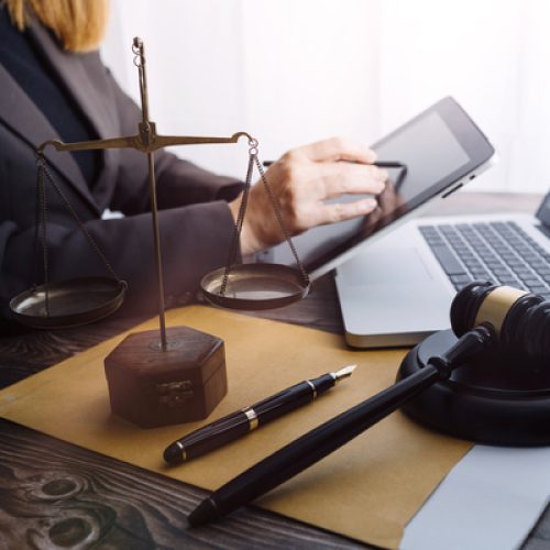 Justice and law concept.Male judge in a courtroom with the gavel, working with, computer and docking keyboard, eyeglasses, on table in morning light